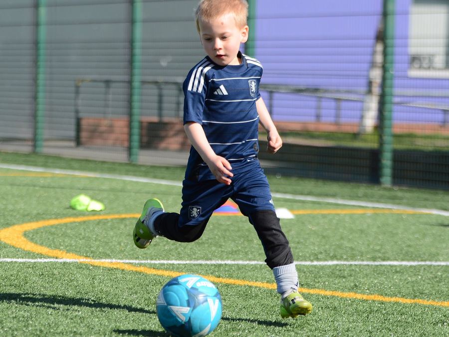 A young player running onto the ball during an M11 Football Coaching session