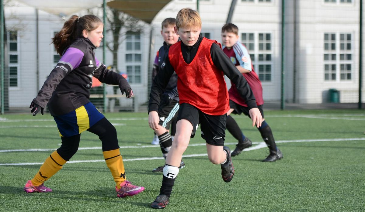 Boys and girls competing for the ball during an M11 Football Coaching session in Dudley