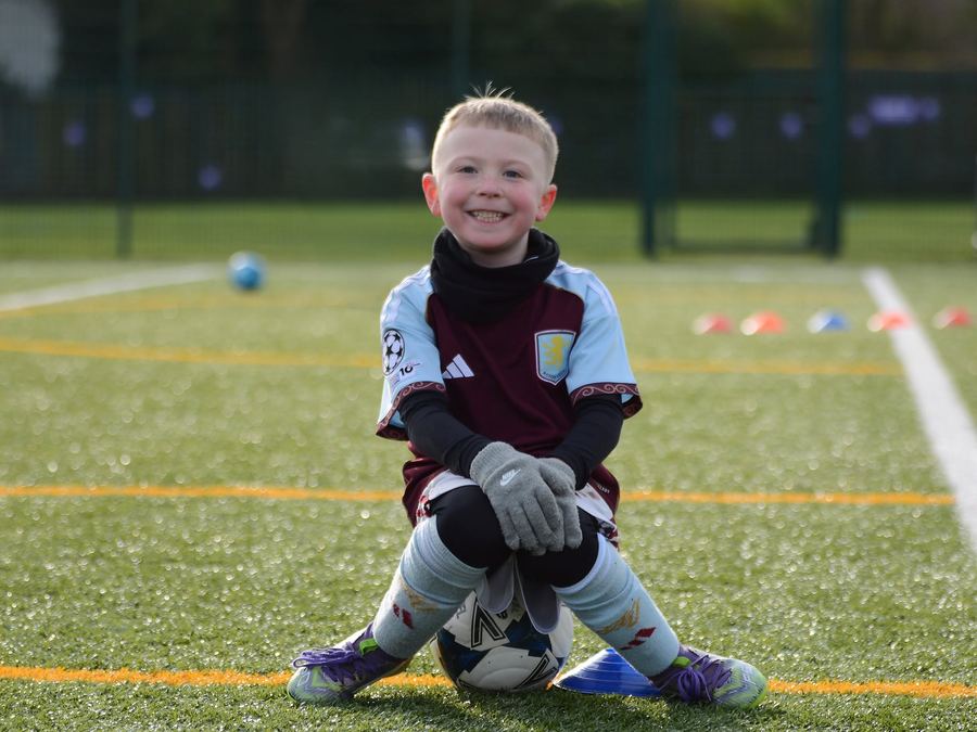 A young goalkeeper smiling on the pitch at an M11 session