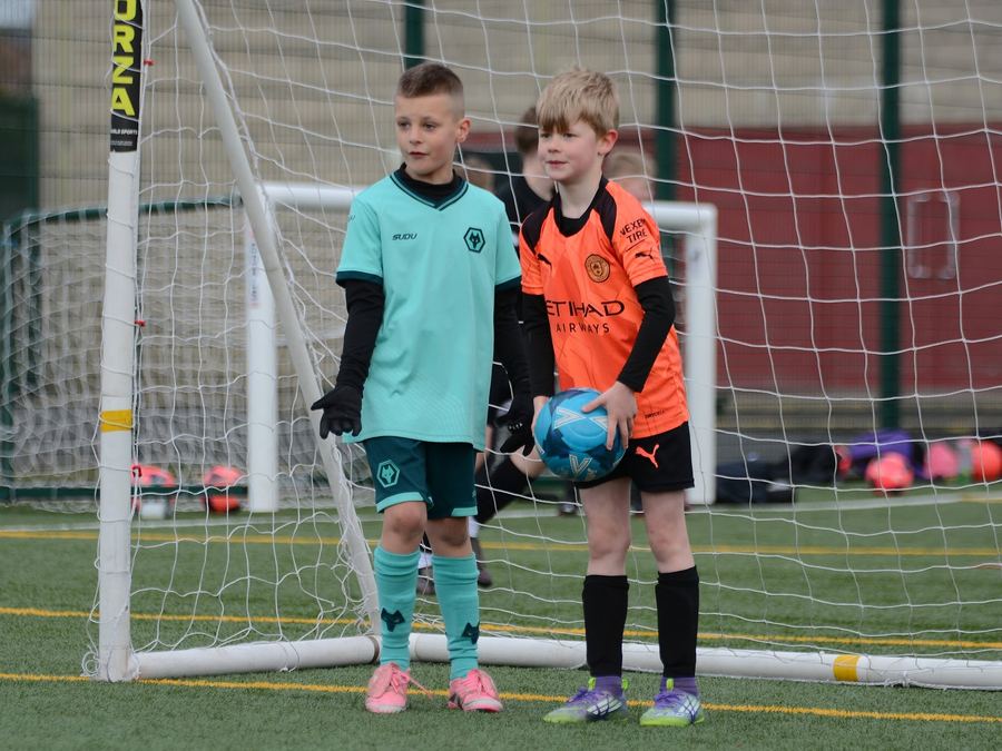 Two young players with a ball in front of the goal at an M11 session