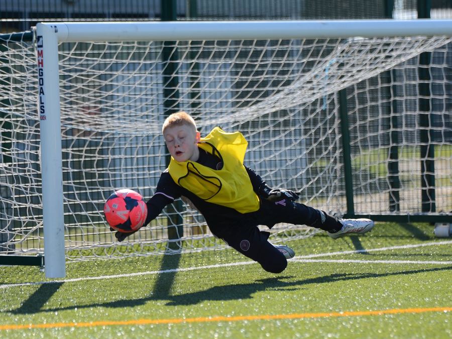 A young goalkeeper making a diving save at an M11 Football Coaching session